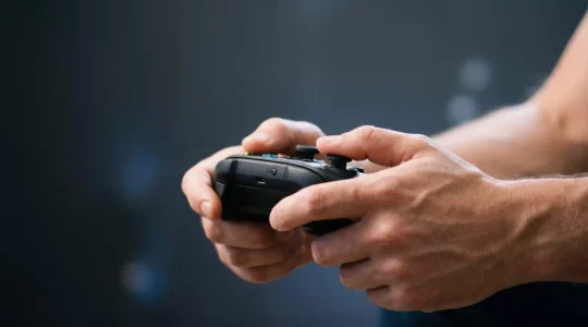 Close-up of hands gripping a game controller with dramatic lighting highlighting tactile engagement and finger positioning during gameplay