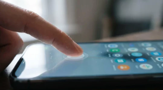Close-up of fingers performing long-press gesture on smartphone screen revealing contextual menu